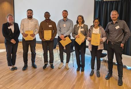 Best Young Author Award finalists at SIMS 2025 together with SIMS president T. Komulainen (left) and NOC Chair K. Thorsen (right). The winners of the award were Nawa Punabantu and Lucas Cammann (3rd and 4th from the left).